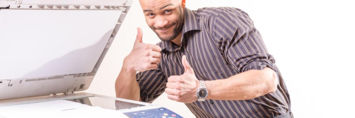 happy worker standing at open copier smiling, thumbs up